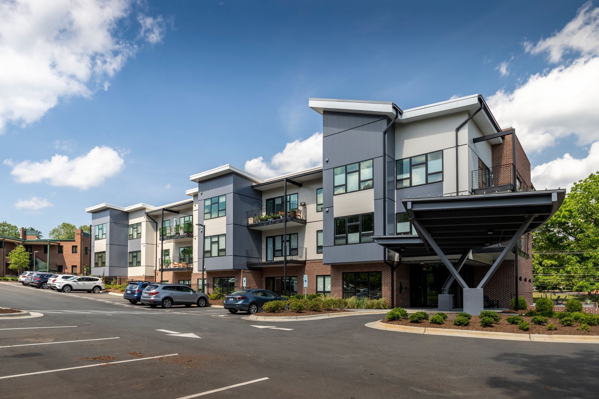 A large apartment building with a parking lot in front of it.
