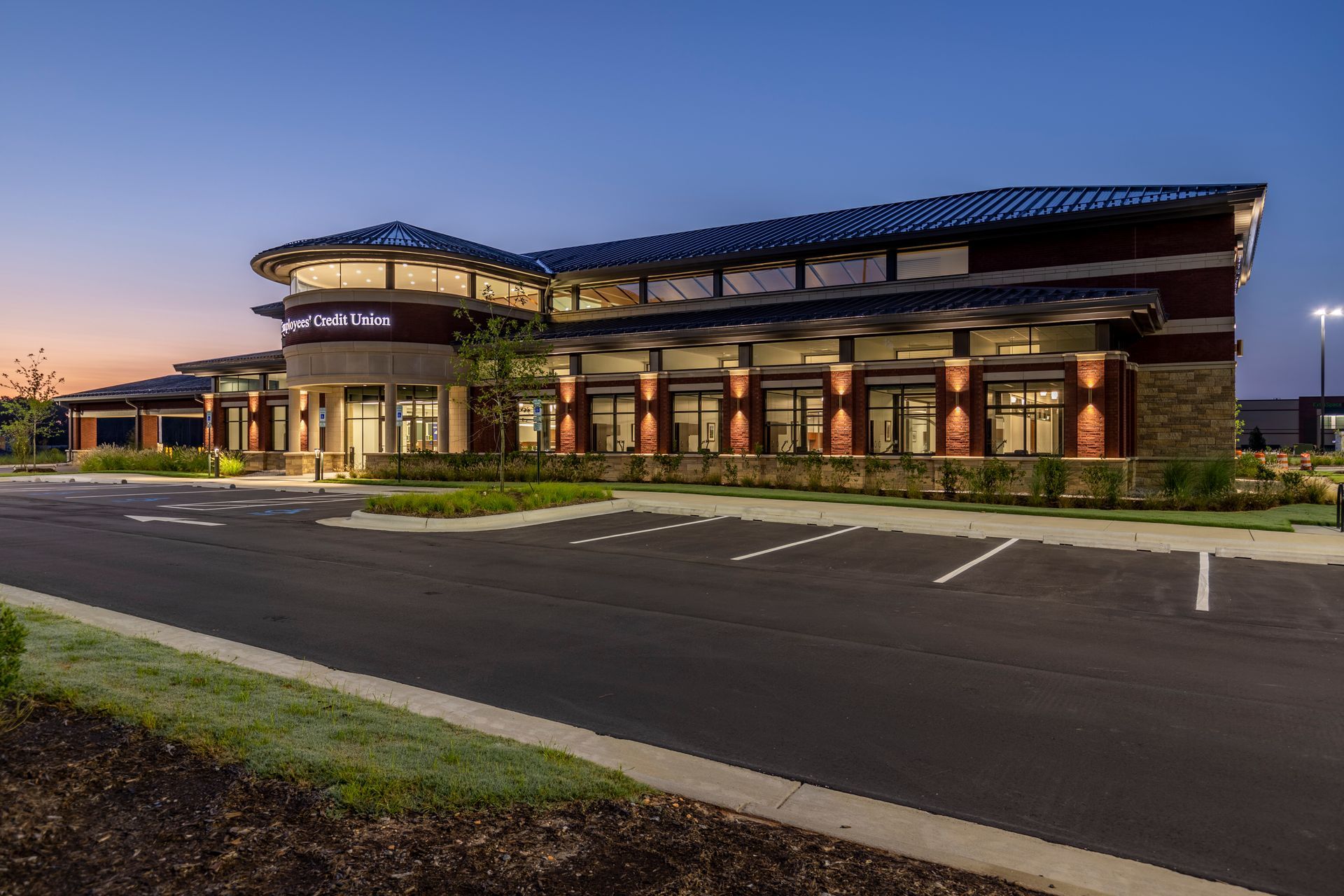 A large building with a lot of windows and a parking lot in front of it.