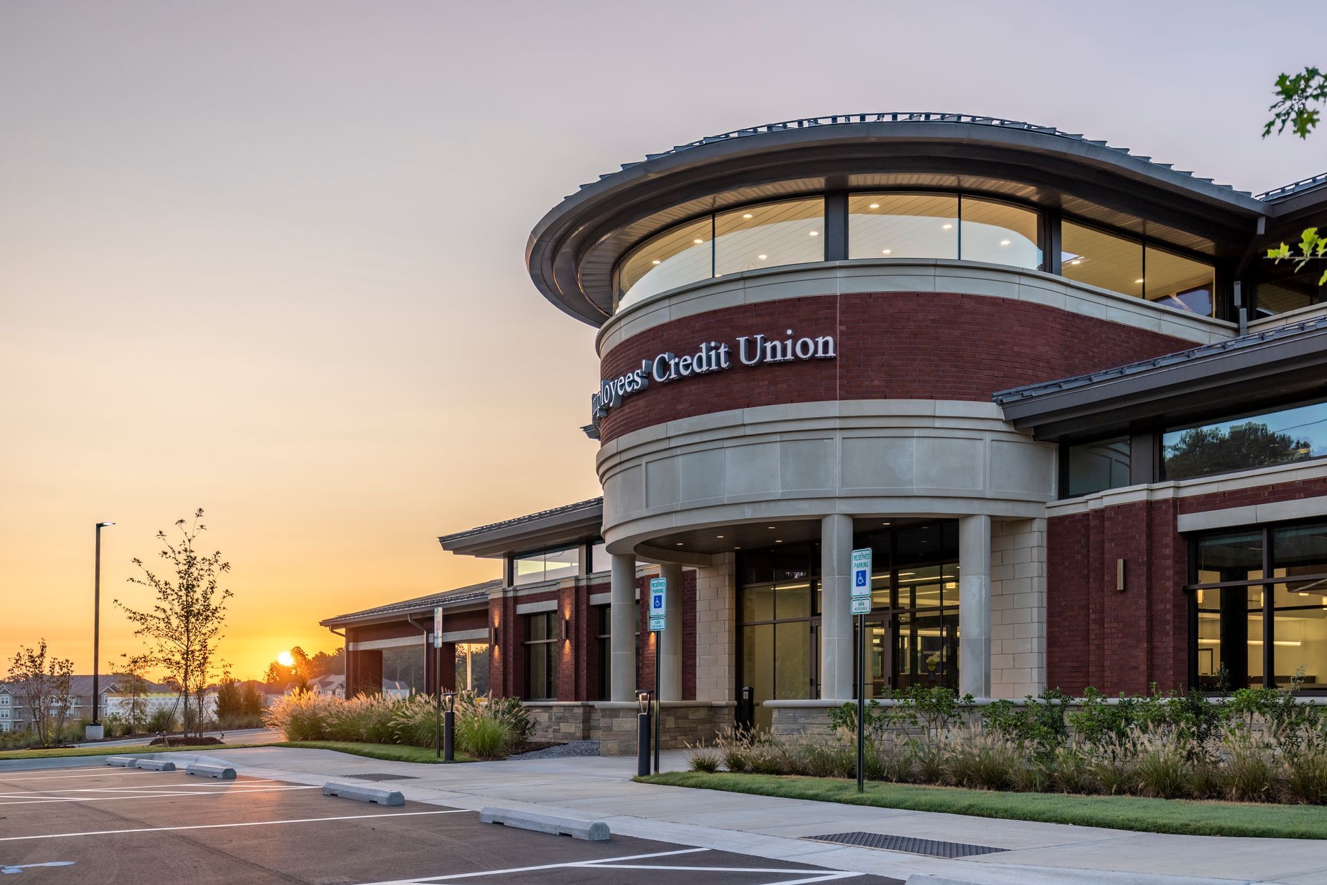 A large brick building with a lot of windows and a sunset in the background.