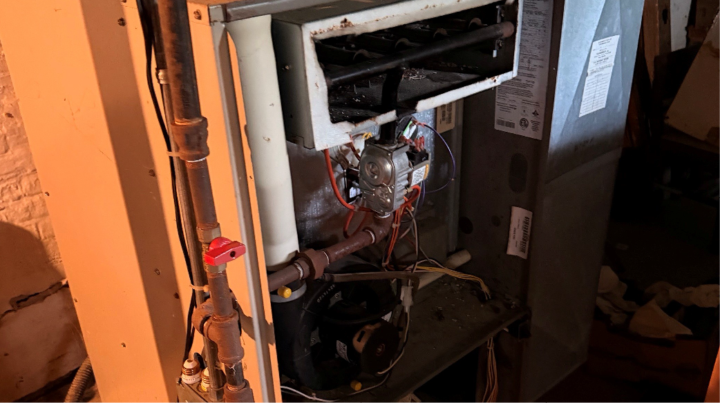 Open furnace with exposed wiring and components in a utility closet