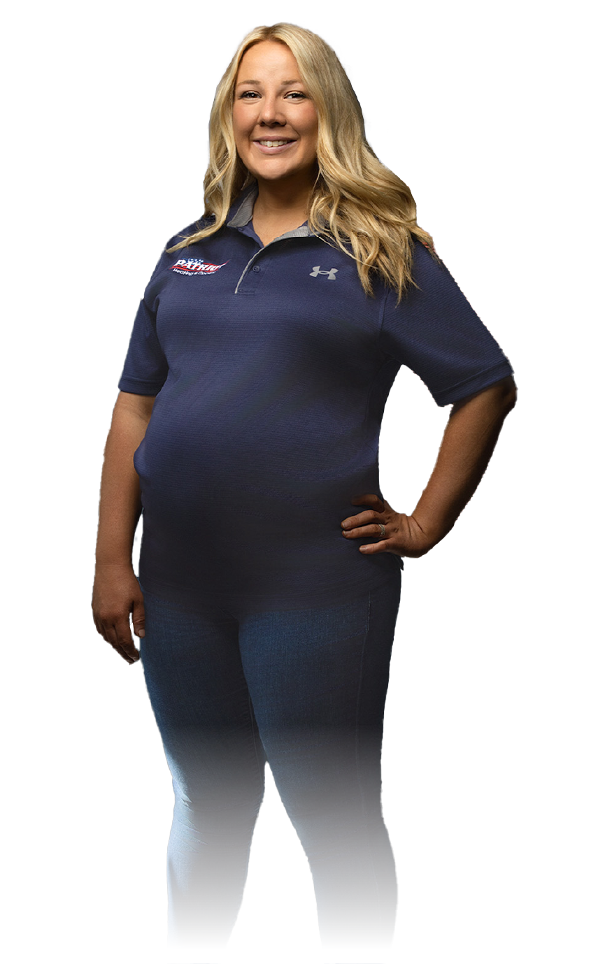 Smiling woman in a navy polo and jeans stands with one hand on her hip against a white background