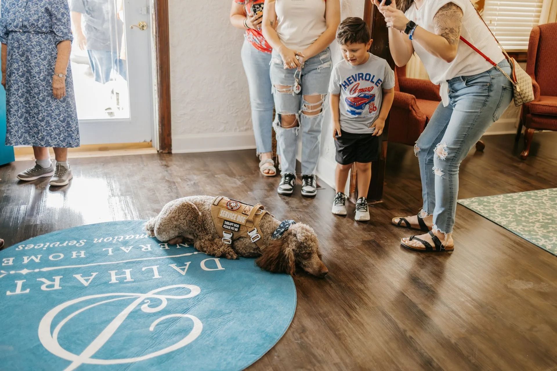 A group of people are standing around a dog laying on the floor.