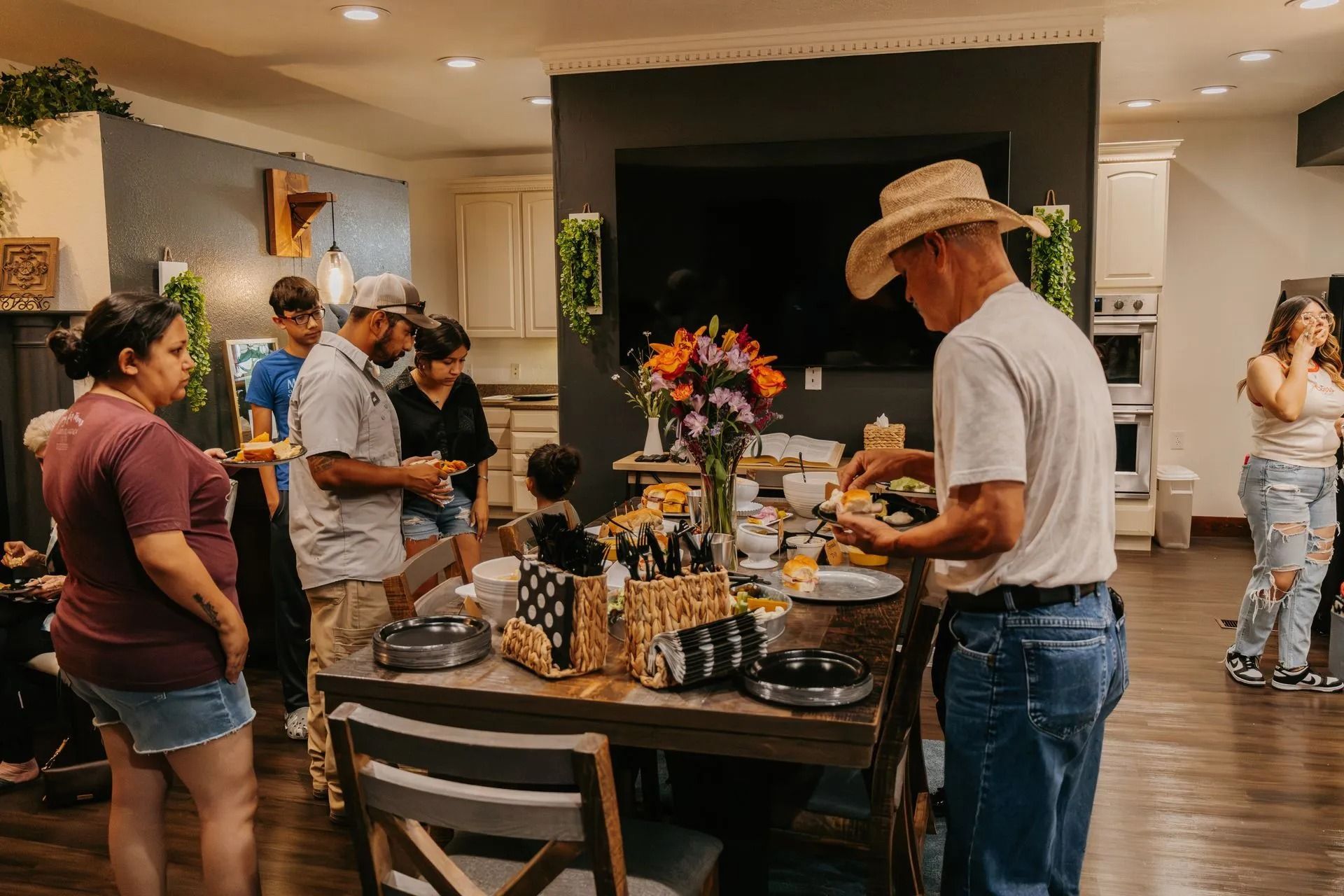 A group of people are standing around a table in a living room.