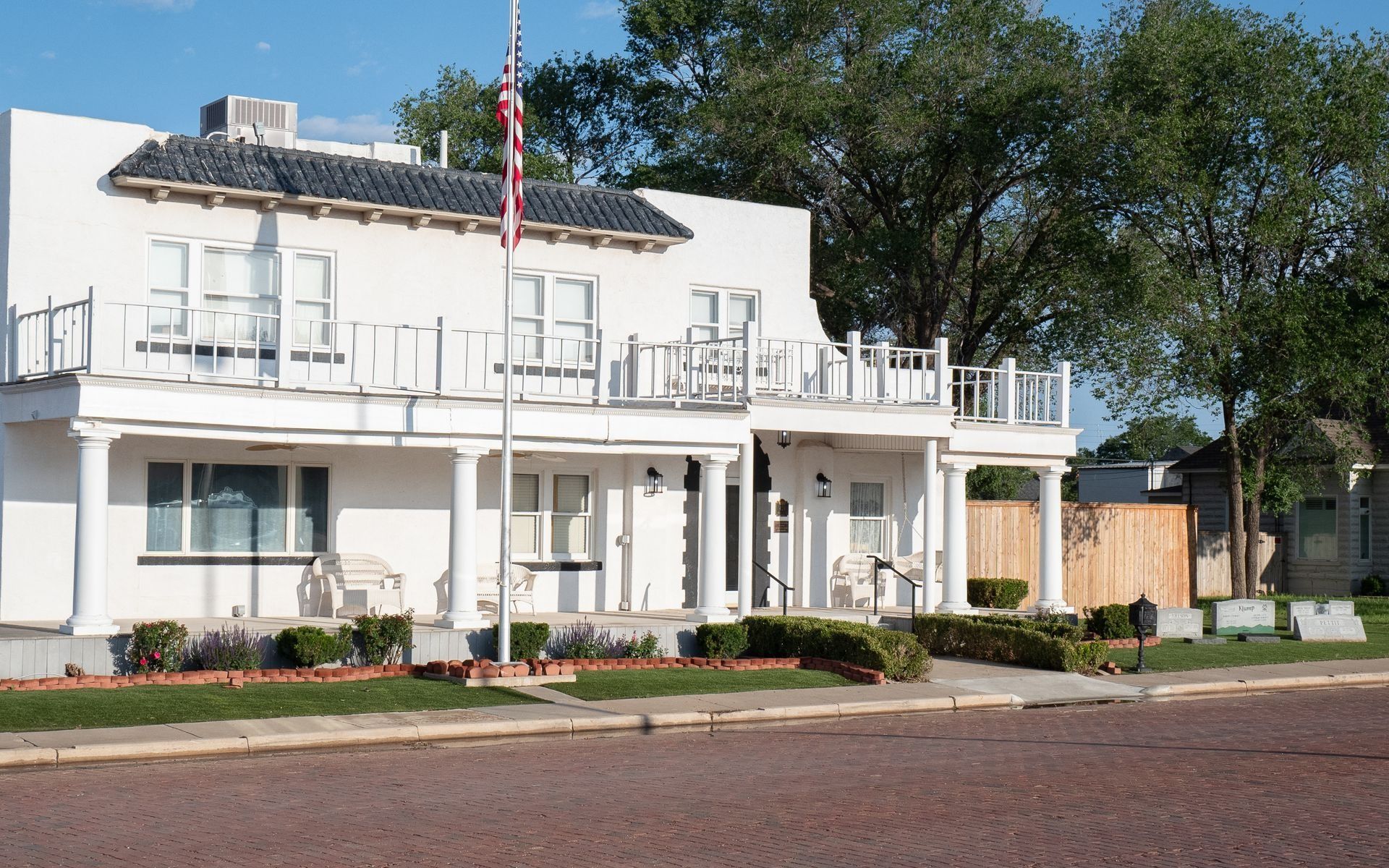 A white house with a balcony and an american flag in front of it