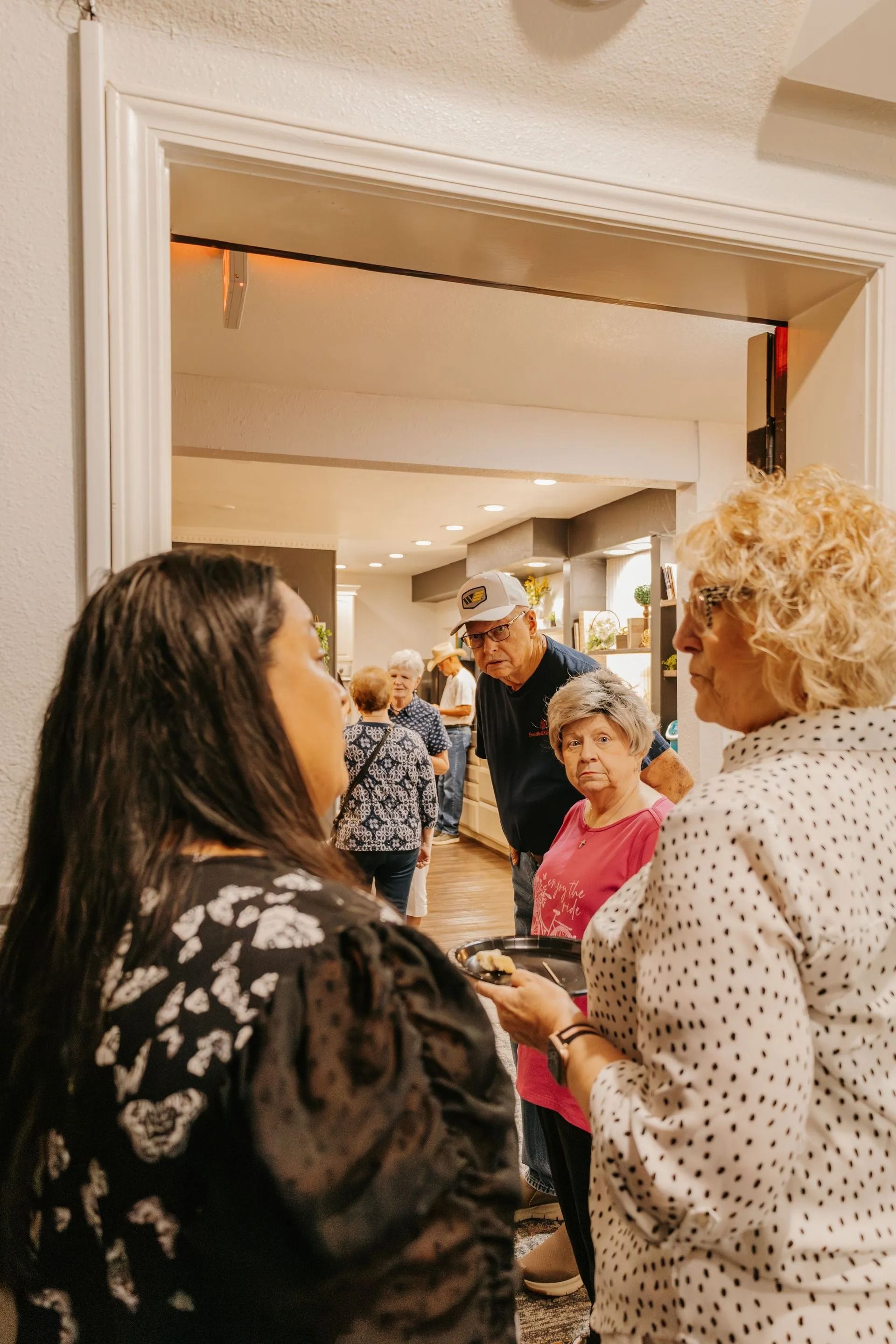 A group of people are standing in a room talking to each other.