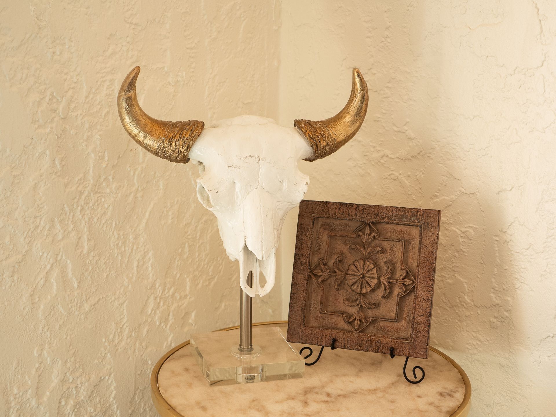 A bull skull with gold horns is sitting on a table next to a plaque.