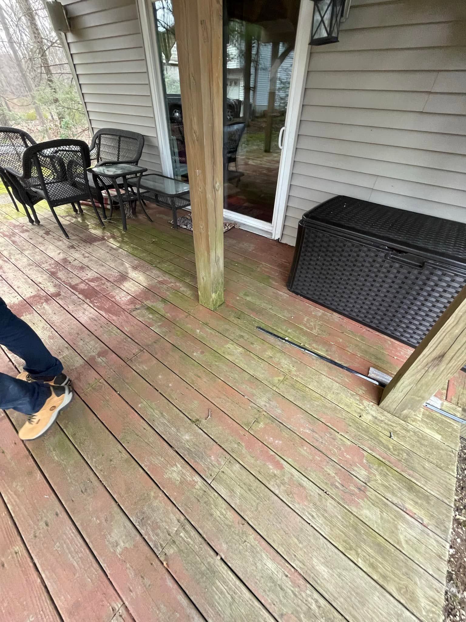 Wooden backyard deck with chairs, sliding glass door, and a black storage box; a person’s foot is visible at left.
