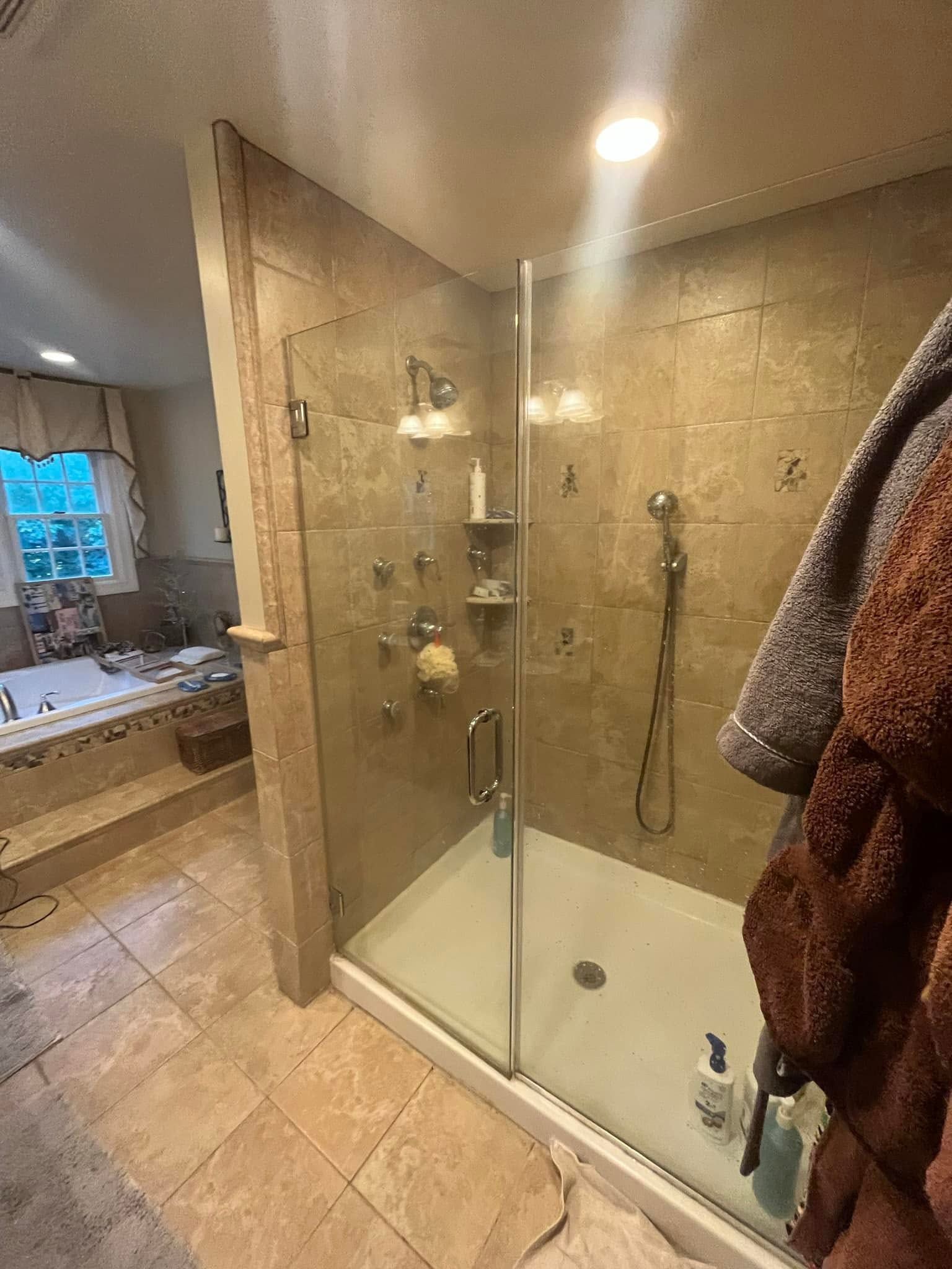 Modern bathroom with glass shower stall, beige tile, and a window by the sink.
