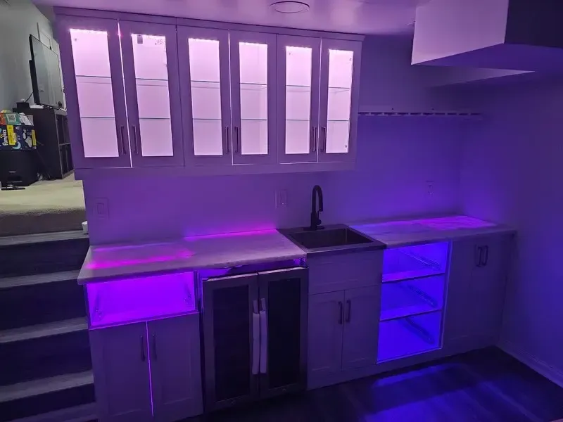Purple-lit modern kitchen with gray cabinets, window, sink, and under-cabinet lighting