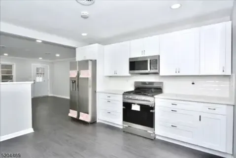 Bright modern kitchen with white cabinets, stainless steel appliances, and gray flooring