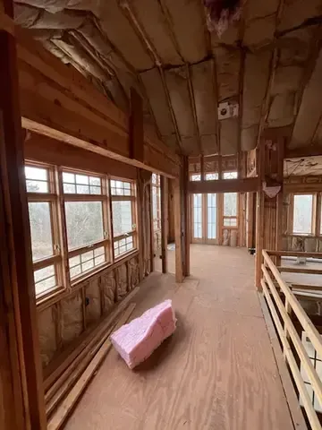 Wooden interior hallway with windows, exposed beams, and a pink cushion on the floor