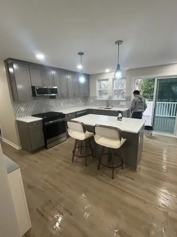 Modern kitchen with island, pendant lights, and a person near the sliding glass door
