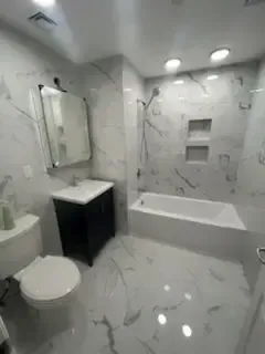 Modern white bathroom with tub, toilet, sink vanity, and tiled walls