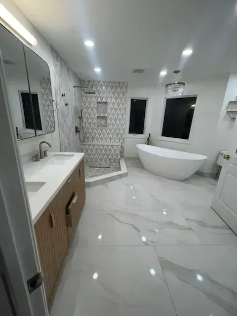 Bright modern bathroom with marble tile floor, freestanding tub, vanity, and walk-in shower