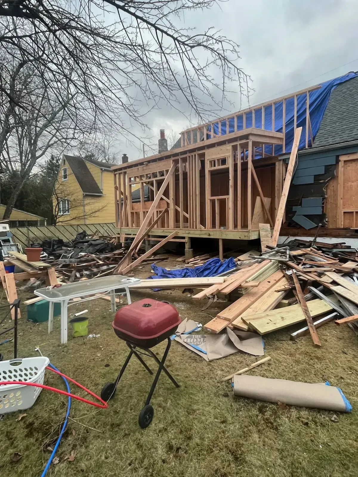 House under construction with collapsed roof and scattered lumber after storm damage