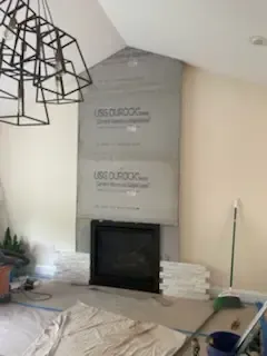 Living room fireplace with gray surround, stacked white tile, and a modern black chandelier in the corner
