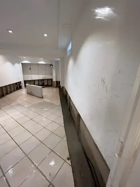 Empty white tiled hallway with low wall panels and bright ceiling lights