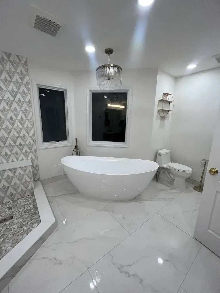 Modern white bathroom with a freestanding tub, glass shower, tiled floor, and large mirror