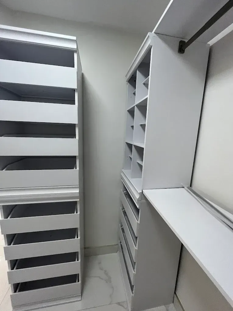 White walk-in closet with built-in shelves and drawers on both sides.