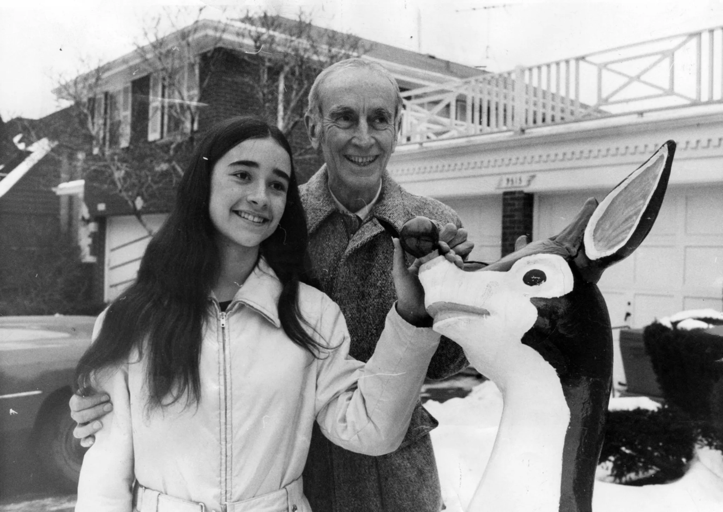 A man and a girl standing next to a stuffed animal