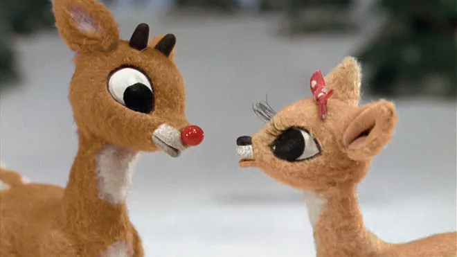 Two stuffed reindeer are standing next to each other in the snow.