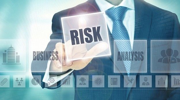 A man in a suit and tie is holding a card with the word risk on it.