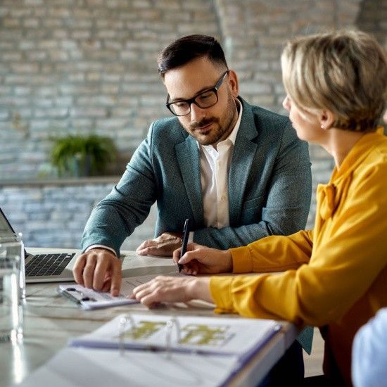 A man and a woman are sitting at a table looking at papers.