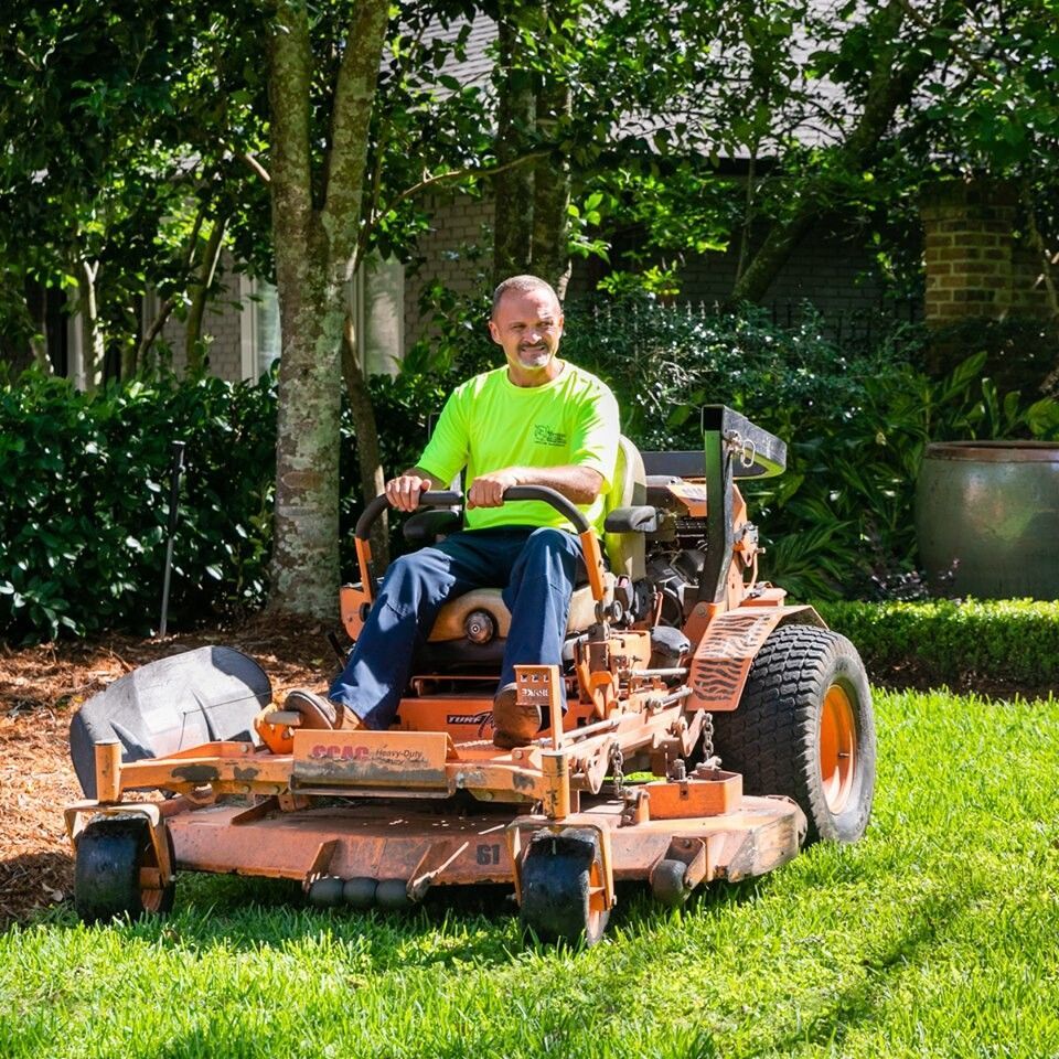 A man is sitting on a lawn mower in a yard.