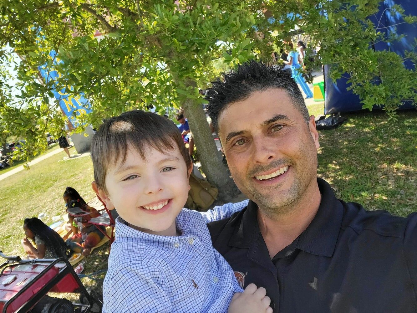 A man is holding a little boy in his arms in a park.
