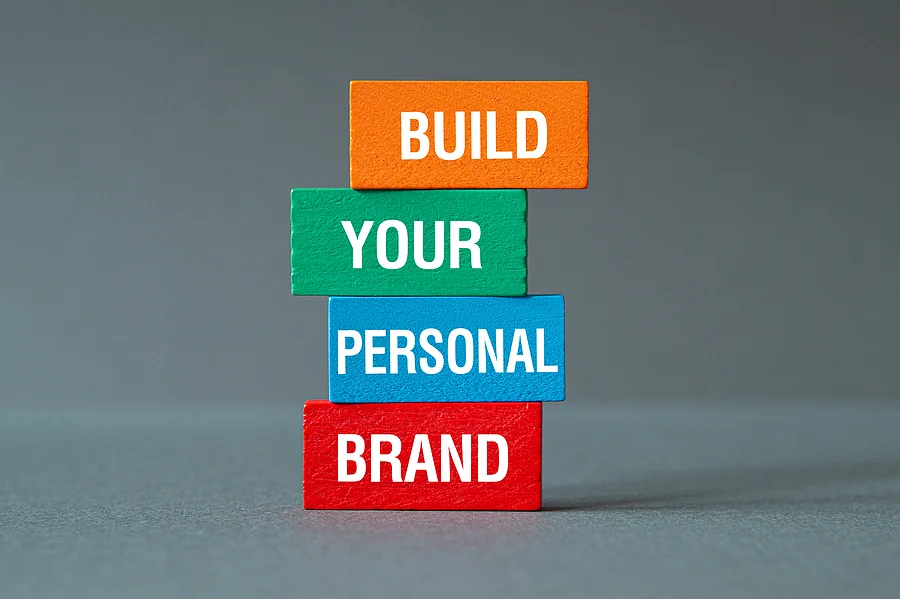 A stack of wooden blocks with the words `` build your personal brand '' written on them.