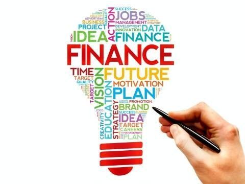 A hand is holding a pen in front of a light bulb that says finance