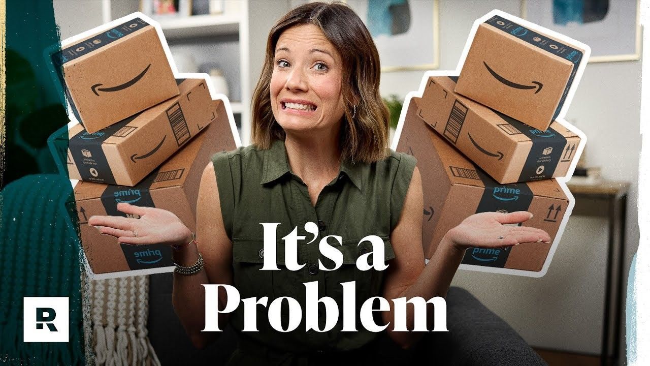A woman is sitting on a couch holding a stack of amazon boxes.