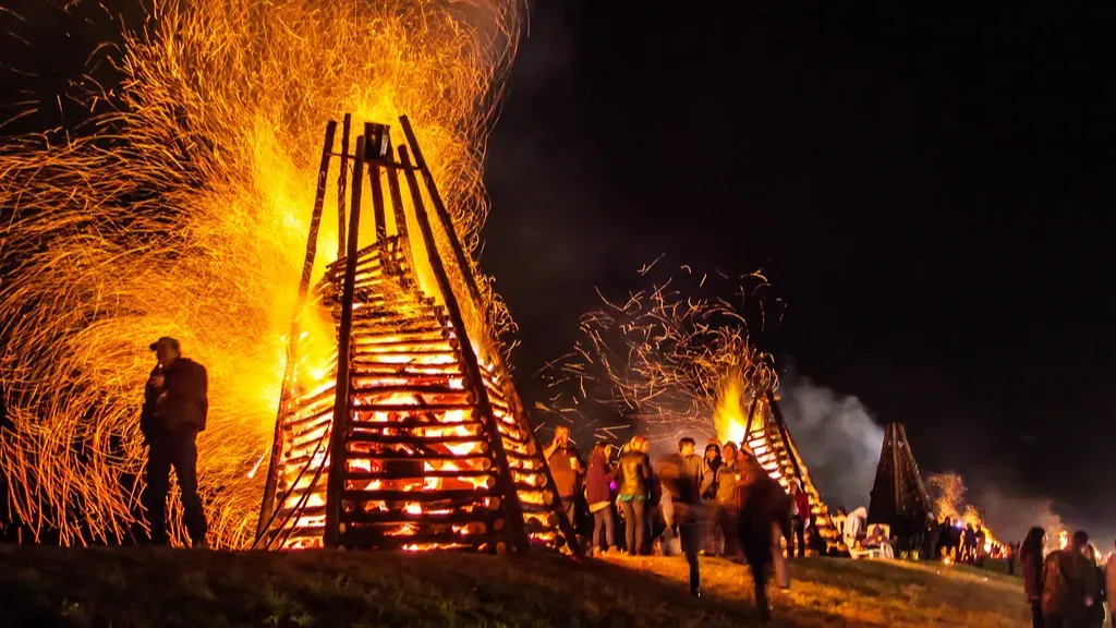 Large bonfires ablaze at night with people watching.