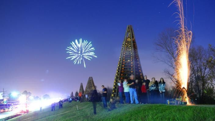 People watching fireworks near a wooden structure at night.