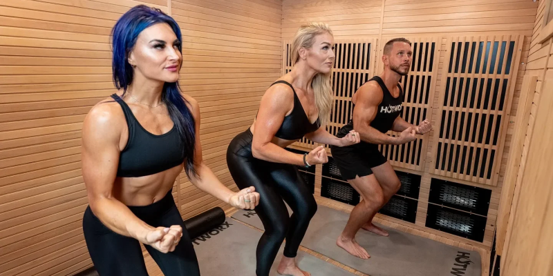 Three women doing a cable workout in a wood-paneled gym room