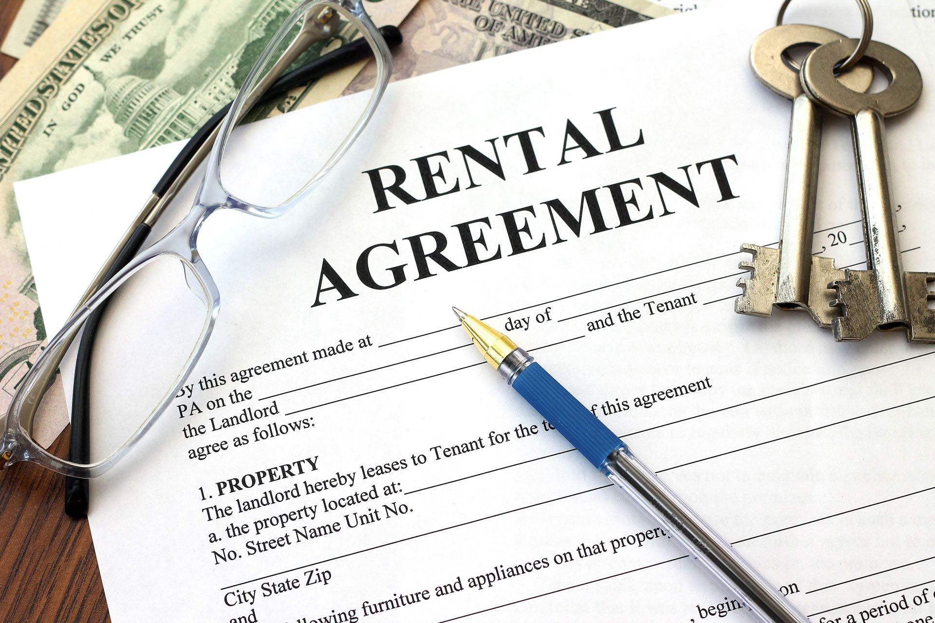 Rental agreement document with glasses, pen, keys, and cash.