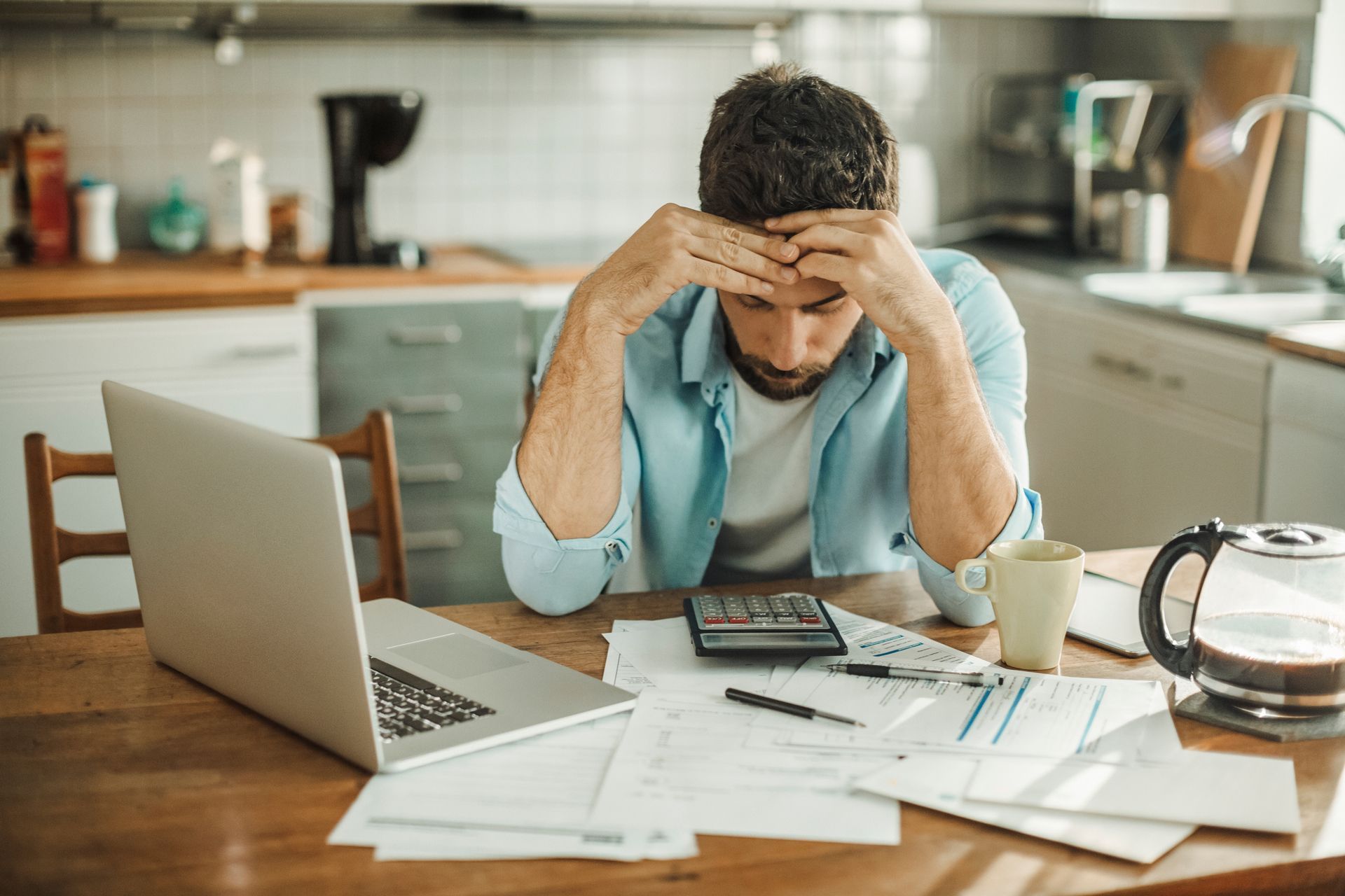A man is sitting at a table with a laptop and a calculator.