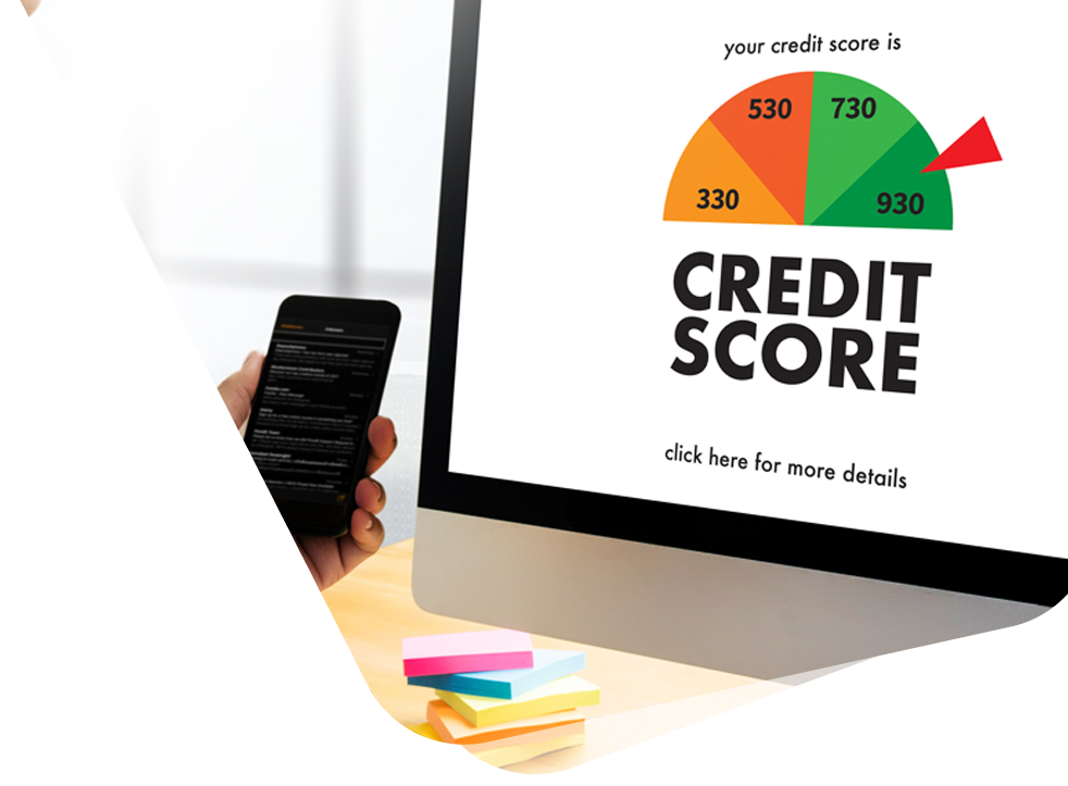 A person is holding a cell phone in front of a computer screen showing a credit score.