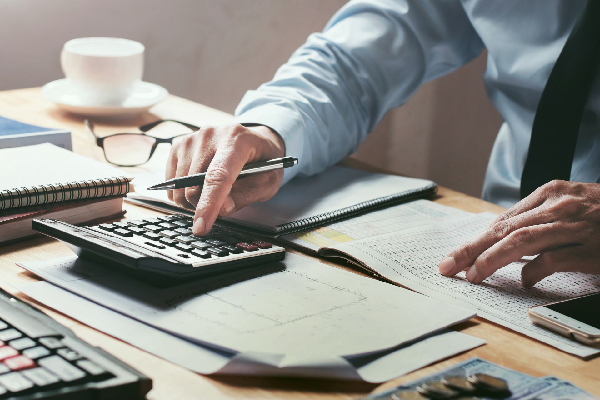 A man is using a calculator and a pen at a desk.