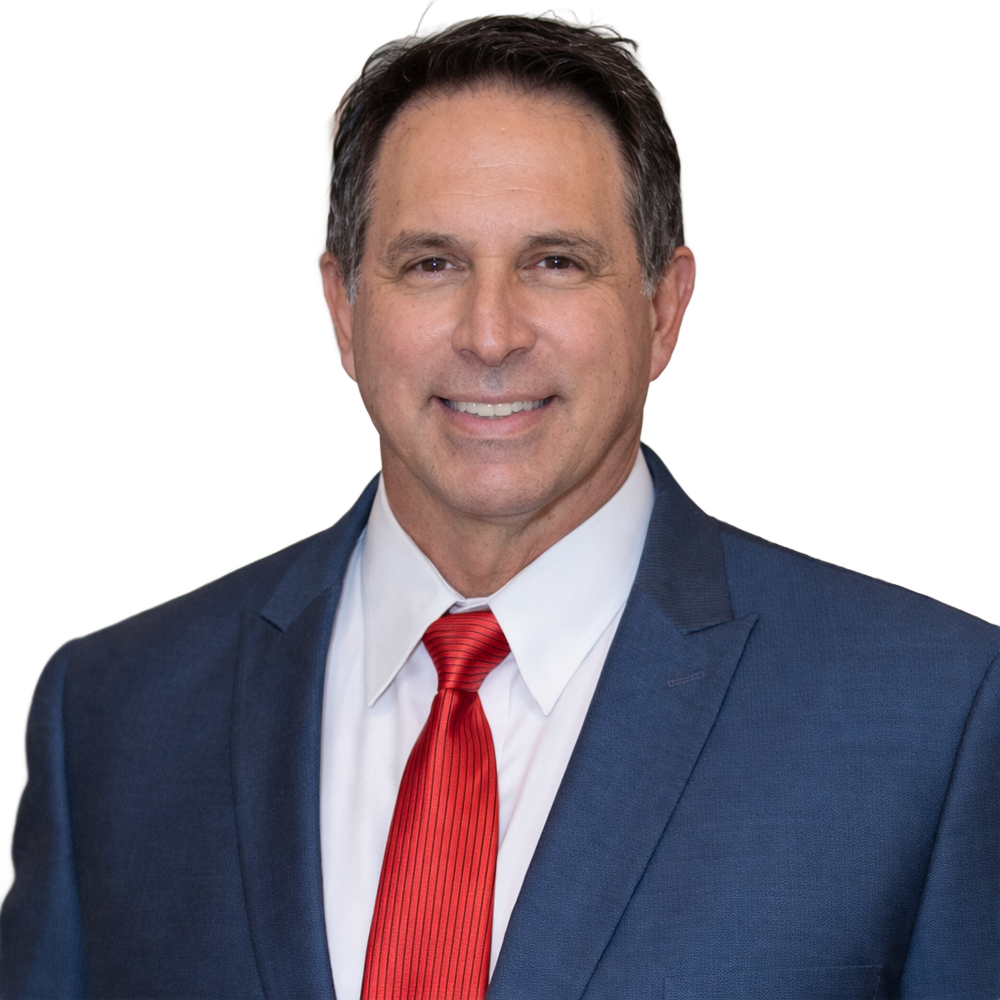 Person in a dark suit and white shirt smiling with hands folded against a white background.