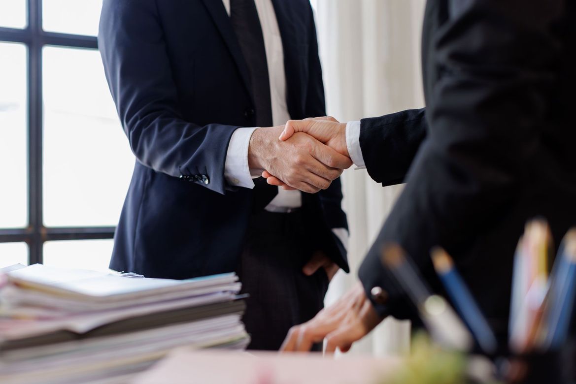 Businesspeople shaking hands across a desk in an office