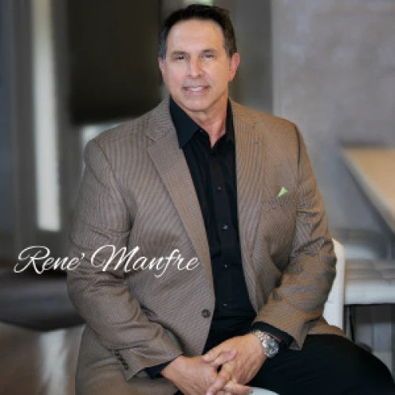 Man in tan blazer over black shirt, smiling.