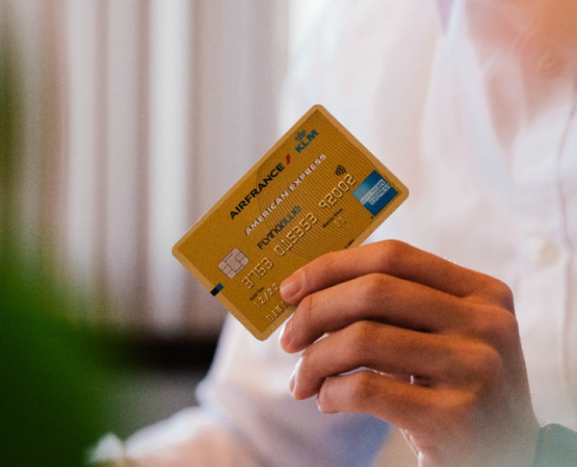 A person is holding a gold american express credit card