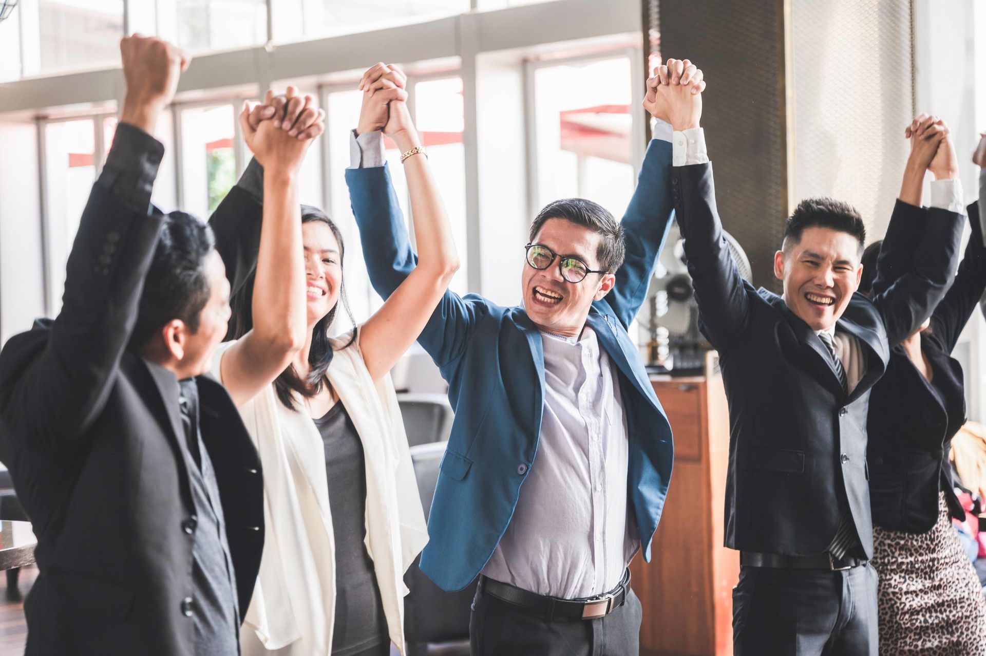A group of business people are holding their hands in the air.