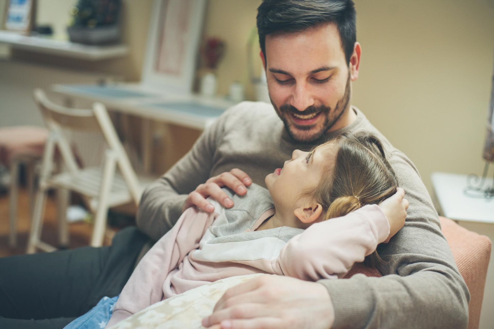 A man is sitting on a couch holding a little girl.