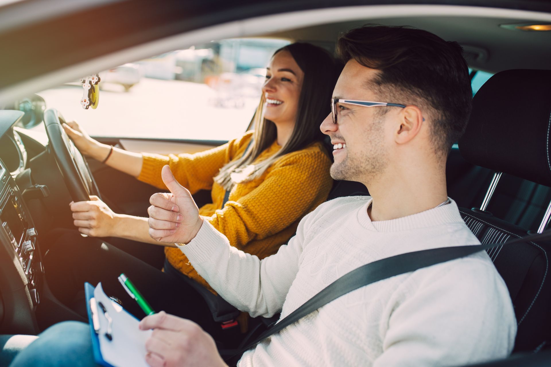 Two people in a car smiling and giving a thumbs-up, with one driving and holding a phone Two people in a car smiling and giving a thumbs-up, with one driving and holding a phone