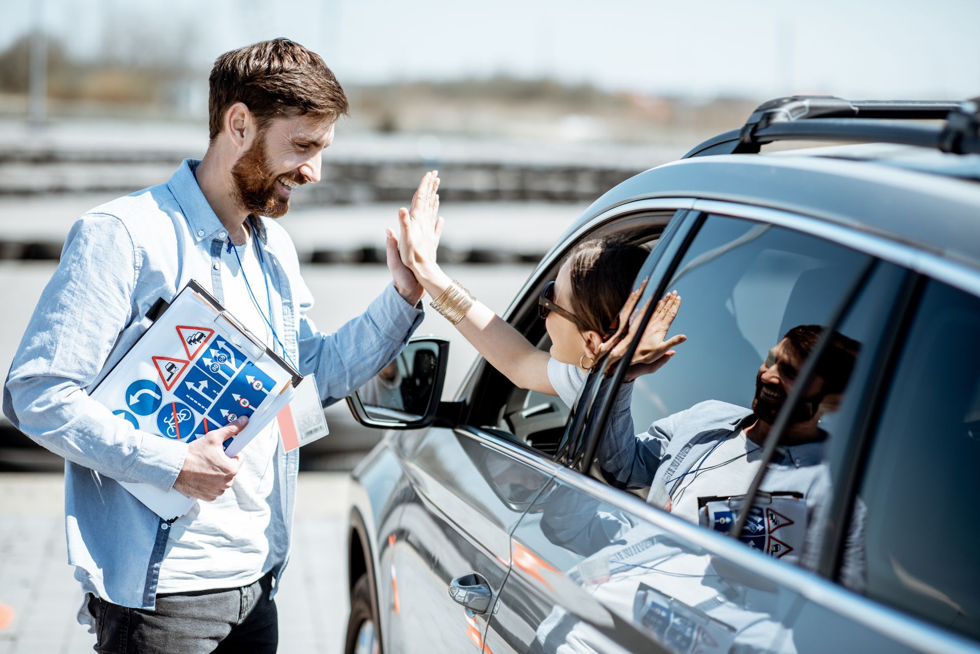 Man handing a flyer to a driver through a car window at a roadside stop Man handing a flyer to a driver through a car window at a roadside stop