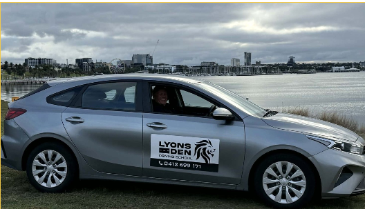 Silver sedan with Lyon’s logo parked by the water under a cloudy sky Silver sedan with Lyon’s logo parked by the water under a cloudy sky