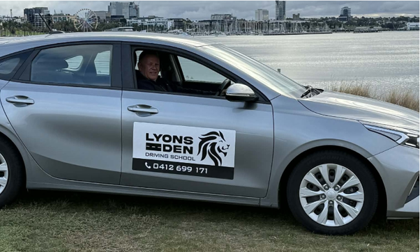 Silver Lyons Eden car parked by water with a driver visible and company logo on the door Silver Lyons Eden car parked by water with a driver visible and company logo on the door