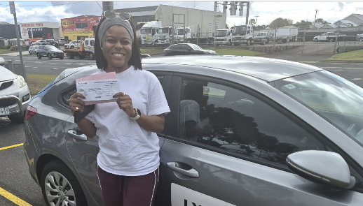 Woman smiling beside a silver car in a parking lot, holding up a document. Woman smiling beside a silver car in a parking lot, holding up a document.